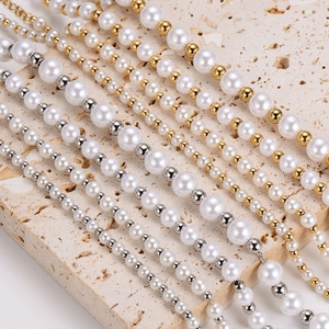 Retro pearl and metal bead necklaces displayed on a beige stone platform