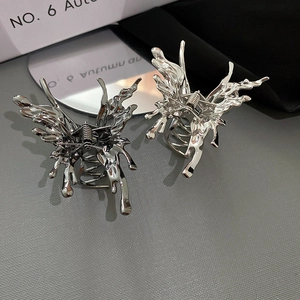 Detail of butterfly hair clips showing liquid metal texture and spring-loaded claw grip