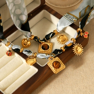 Detail of silk scarf necklace with gold heart and sun pendants on a jewelry display