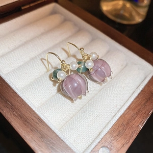 Macro detail of pink flower earrings with pearls on a soft jewelry display tray