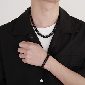 Detail of black Cuban link chain necklace and bracelet set on a male model outfit