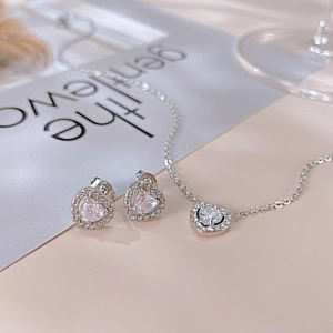Macro view of silver heart-shaped necklace and stud earrings set with cubic zirconia