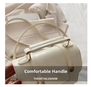 Close-up of creamy white textured PU leather handbag with cylindrical handle and gold buckle