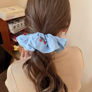 Close-up of light blue scrunchie with red cherry embroidery and elegant white pearls
