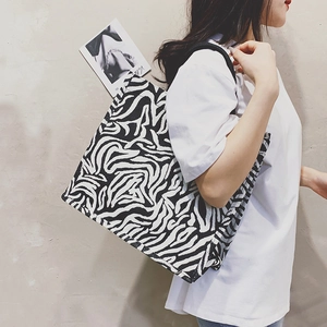 Zebra print canvas tote bag with black shoulder straps shown on model for daily use