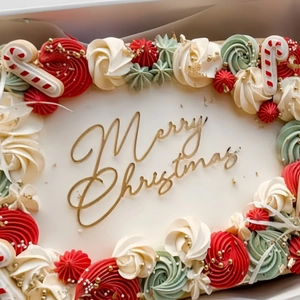 Golden Merry Christmas acrylic cake topper on festive red and green cream holiday cake