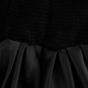 Detailaufnahme des Kontrasts zwischen Rippstrickgewebe und plissiertem Satin am Oberteil