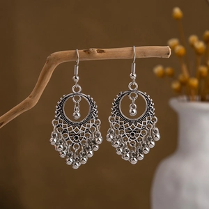 Detailed view of bohemian silver drop earrings with metallic beads and tassel texture