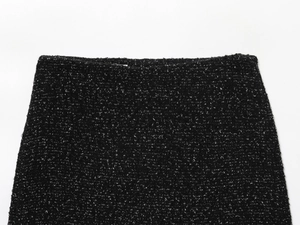 Gros plan détaillé de la taille d'une jupe en tweed noir montrant la texture du tissu