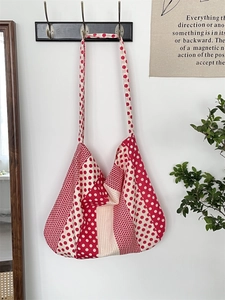 Detailed close-up of red and white polka dot canvas tote bag hanging on a metal hook