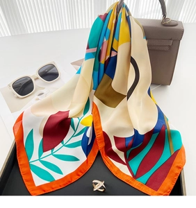 Artistic printed silk scarf draped on a handbag with sunglasses for a luxury look