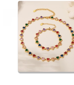 Detailed close-up of gold heart necklace and bracelet set with colorful zircons