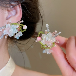 Primer plano de pendientes de flores de cristal hechos a mano con delicadas cuentas verdes y rosas