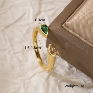 Detail of adjustable gold ring featuring pear-cut emerald and champagne zircon stones