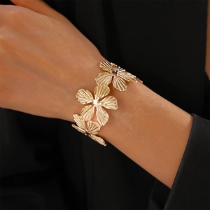Detail of gold floral cuff bracelet featuring three textured blooming metal flowers