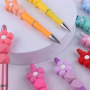 Colorful DIY beaded pens with silicone flower shapes on white display stand