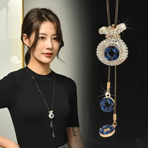Detail of gold tone fortune bag pendant necklace with blue zircon and long tassels