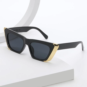 Fashionable black cat-eye sunglasses with gold metal trim and dark grey lenses on stand