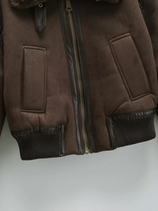 Detail view of coffee brown suede jacket with leather trim and metal zipper