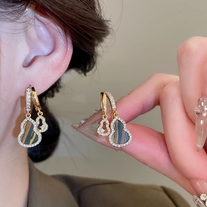 Detail of vintage gourd earrings with gold frame, pavé zircons and tiger eye stone