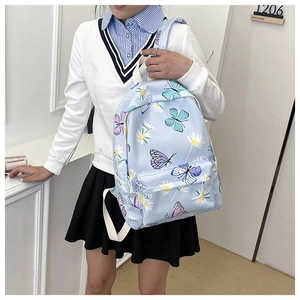 Blue butterfly backpack with floral print shown on model in a stylish indoor setting