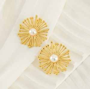 Detailed view of gold sunburst flower earrings with elegant central pearl accents