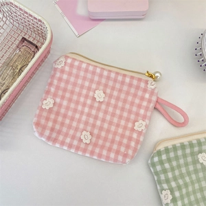 Détail de broderie florale en dentelle sur porte-monnaie en toile rose avec perle