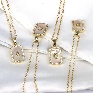 Detail of 18K gold plated square pendant necklace with shell inlay and zircon letters