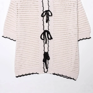 Off-white crochet knit polo cardigan with black bows and scalloped edge trim