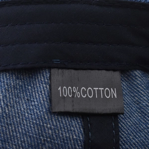 Gros plan sur l'étiquette 100% coton et les coutures de la casquette en denim bleu