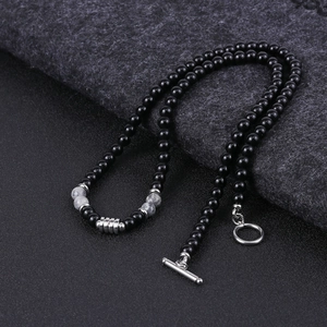 Detail of beaded necklace with tiger eye stones and silver T-bar clasp on dark fabric