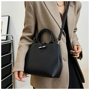 Detailed close-up of black lychee grain leather bucket bag with silver bamboo toggle closure