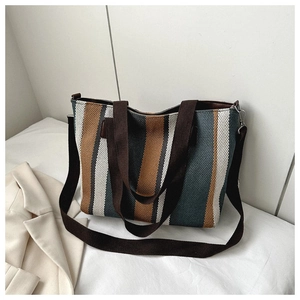 Detail of striped canvas tote bag with brown handles and a detachable shoulder strap