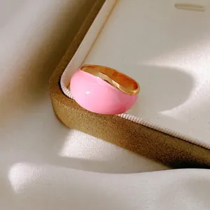 Minimalist pink enamel round ring with gold metal edges shown on a soft jewelry box