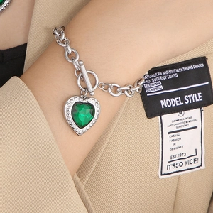 Macro detail of OT toggle clasp and heart-shaped green crystal on silver-tone chain