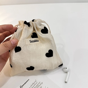 Close-up of heart pattern texture on a cream drawstring pouch with Sozakka tag
