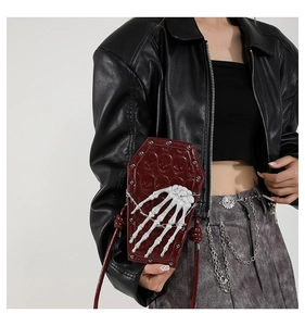Deep burgundy coffin-shaped crossbody bag featuring embossed skulls and 3D skeleton hand