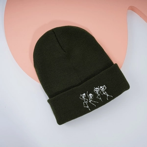 Détail de la broderie squelettes blancs sur un bonnet en tricot vert foncé