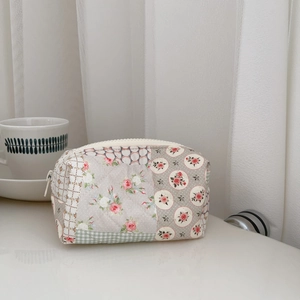 Close-up of floral quilted makeup bag with zipper closure and rustic patchwork design