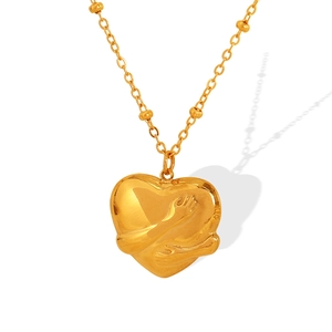 Golden 3D heart necklace with hugging arms pendant on a bead chain over white background