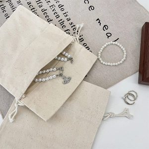 Detail of a drawstring canvas jewelry pouch with pearl necklaces and metal rings