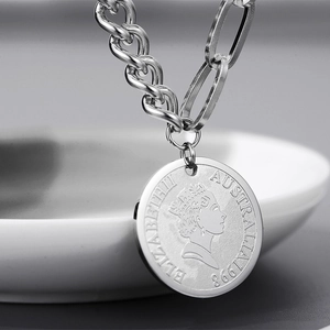 Detailed close-up of silver coin pendant with Queen portrait and Cuban link chain