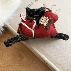 Close-up of red trojan horse fabric hair claw clip on vintage book and wooden surface