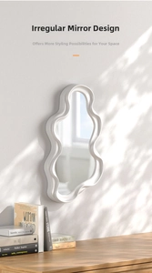 Modern white framed cloud-shaped irregular wall mirror on a wooden desk with shadows