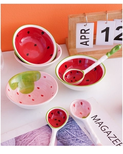 Detail view of watermelon themed ceramic bowls and matching spoons on a white table