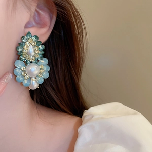 Close-up of model wearing flower-shaped earrings with teal crystals and pearls