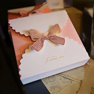 Detail of pink paper gift box with a gold-stamped bow and Thank You lettering