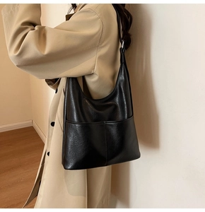 Detail of a black large-capacity tote bag worn with a stylish khaki trench coat