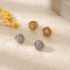 Vintage gold and silver rose earrings with cubic zirconia on textured background