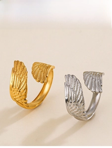 Macro detail of gold and silver feather-shaped open rings with intricate wing textures